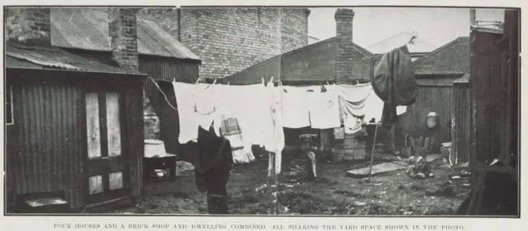 Image: Four houses and a brick shop and dwelling combined, all sharing the yard space shown in the photo