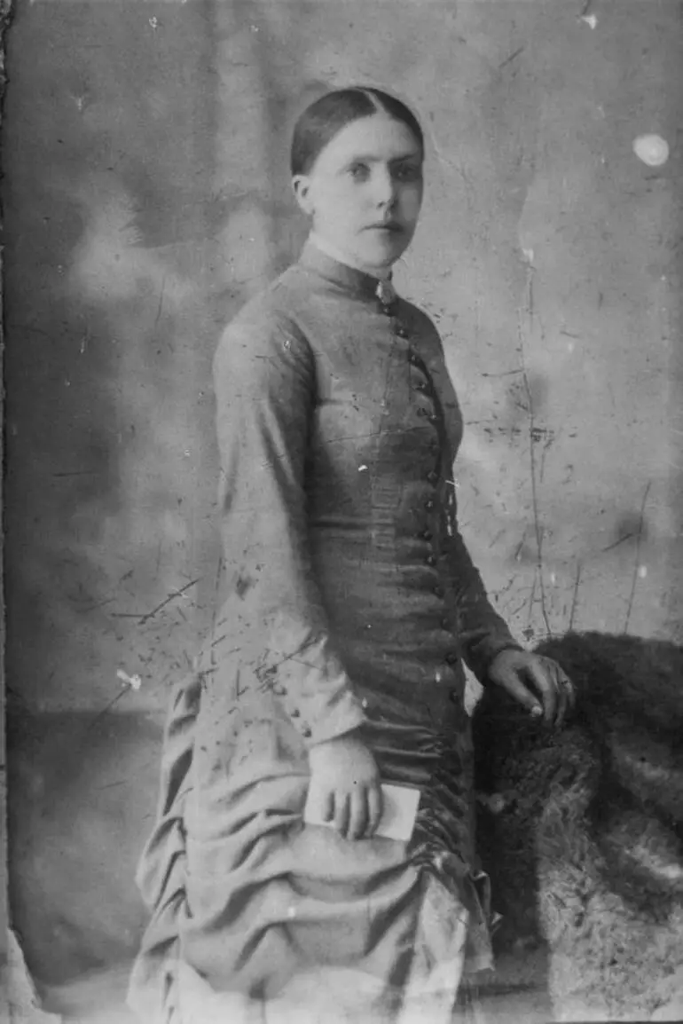 Image: Woman wearing a dark coloured, high necked gown, 1909