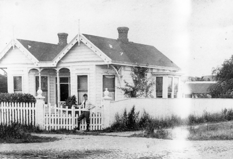 Image: Charles Haigh standing at the gates of an unidentified house