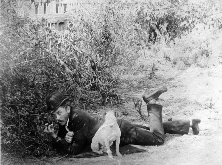 Image: A man laying on the grass with his dog