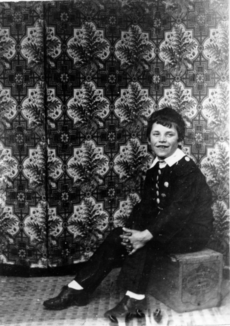 Image: A boy sitting on a box in front of a screen