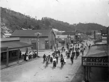 Image: Cyclists in a Greymouth street, passing the premises of Mrs S Beresford, dressmaker, between 1898 and 1905