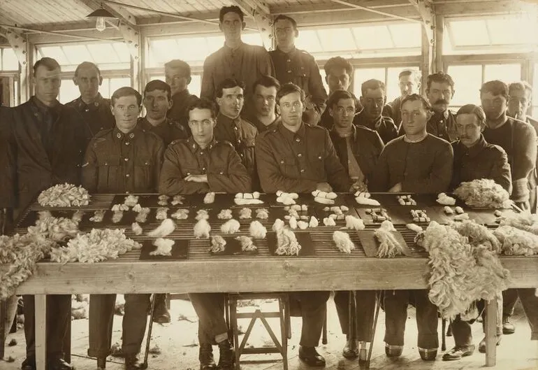 Image: William Gemmell and nineteen unidentified WWI soldiers posed around a display of graded wool samples at Oatlands Park, Surrey, England
