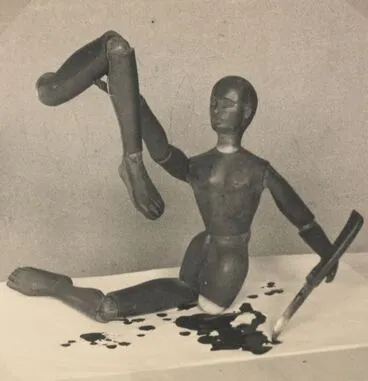 Image: Close up of tabletop set up of artist's mannequin holding up severed 'bloody' leg, with knife in left hand