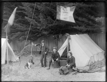 Image: Three unidentified boys, one with an accordian, and another with a penny farthing bicycle, at a campsite, possibly Christchurch district