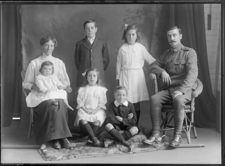 Image: Studio unidentified family portrait, father in soldier's uniform with stirrups and mother with baby girl on knee next to older sons and daughters, Christchurch