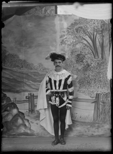 Image: Studio portrait of unidentified young man with large moustache, dressed in medieval nobleman's clothing, with striped tunic, large lace collar, breeches with stockings, cloak and feathered hat, Christchurch