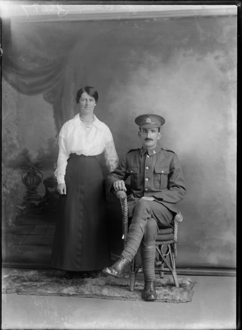 Image: Studio unidentified family portrait, a World War I soldier with moustache, collar and hat badges, sitting alongside wife with pearl necklace and pearl shirt buttons, Christchurch