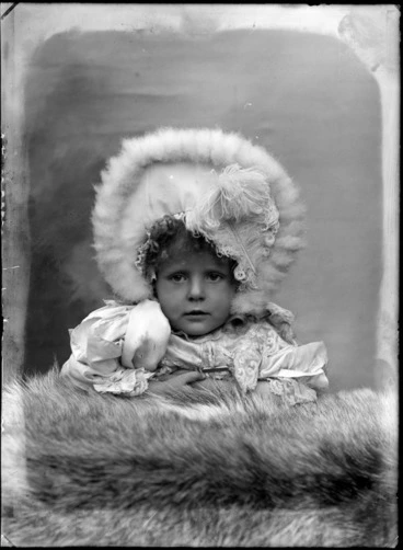 Image: Studio portrait of unidentified small girl, wearing a fur bonnet, probably Christchurch district