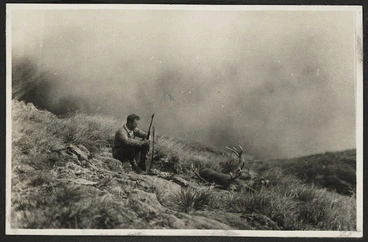 Image: Arthur Gregg on hillside with gun and dead deer