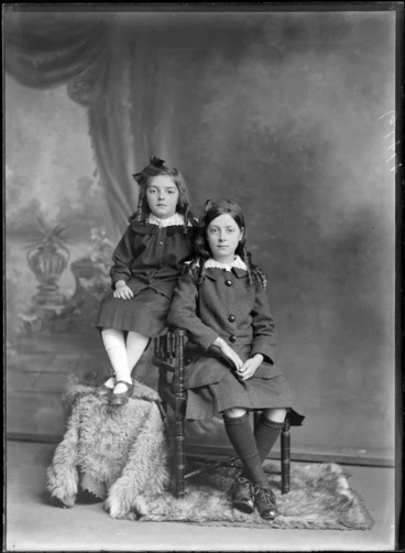 Image: Studio unidentified family portrait of a two young sisters with curly long hair, hair bows and large lace collars, sitting on a wooden chair, Christchurch