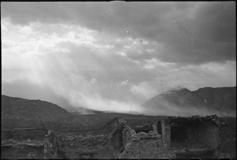 Image: Sunlight breaking through clouds over Cassino lightens up smoke screen laid down following bombing, Italy, World War II - Photograph taken by George Kaye