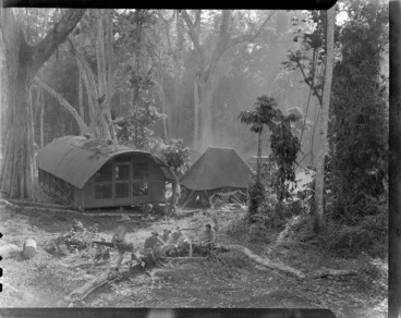 Image: Group of unidentified men sitting in a forest area, at RNZAF (Royal New Zealand Air Force) camp, Guadalcanal, Solomon Islands