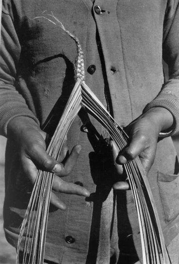 Image: Photograph of a person demonstrating the plaiting and weaving of flax