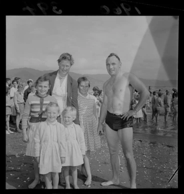 Image: An unidentified man, who just completed the Somes Island Petone swim, on Petone Beach with his wife and four young daughters, Wellington City