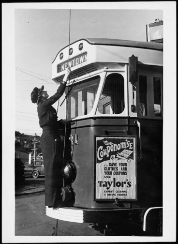 Image: Woman conductor placing the tram pole on the wire
