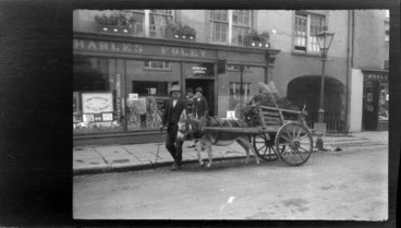 Image: Street scene, man with donkey and cart filled with peat, in front of Charles Foley & Son shop, Killarney, County Kerry, Ireland