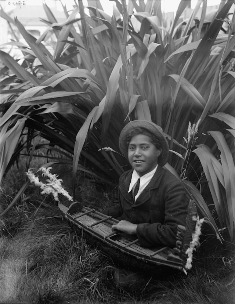 Image: Unidentified Maori child with a small scale model of a canoe - Photograph taken by William Henry Thomas Partington