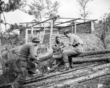 Image: [Members of survey team of 16th NZ Field Regiment trimming a log for their partially completed log cabin, Korea]