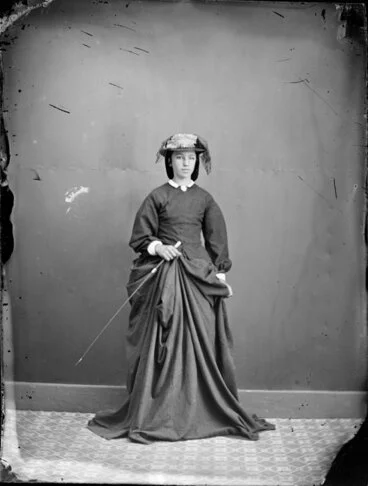 Image: Unidentified young woman with a crop or cane
