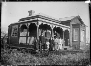 Image: Family group standing on lawn in front of a villa