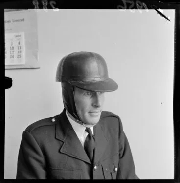 Image: An unidentified official [policeman?] models a safety helmet at the time they became compulsory for motorcyclists