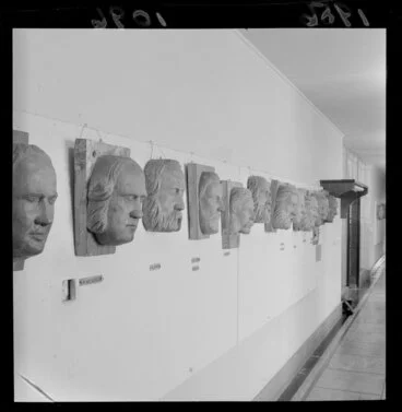 Image: Wooden relief sculptural portraits of prominent Wellingtonians, originally carved for exterior of Wellington Old Identities Hotel, hanging on a wall at Central Library
