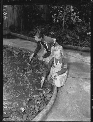 Image: Girl Guide, and a Brownie, working in a garden during Bob a Job Week