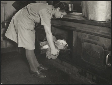 Image: Cook from the Women's Army Auxiliary Corps putting meat in an oven to roast, for men at a World War II military camp in New Zealand