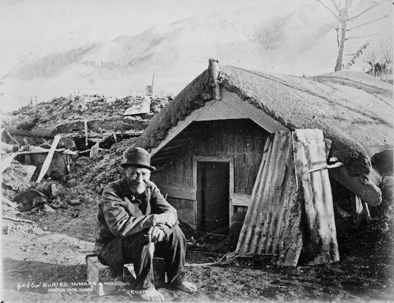 Image: Creator unknown: Photograph of Rewiri outside a buried whare at Te Wairoa, Rotorua district, taken by the Burton Brothers after the 1886 eruption of Mount Tarawera