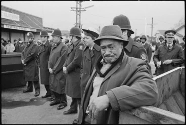 Image: Percy Bush, uncle of the captain of the New Zealand Maori rugby team, standing by police as anti-apartheid demonstrators march by