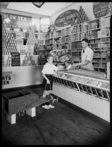 Image: Boy, with his home built trolley, shopping in a Self Help Co-operative grocery store