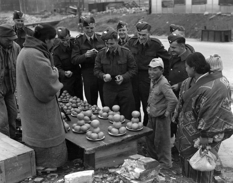 Image: RNZAF personnel attempt to bargain with a Japanese fruiterer at Kure market