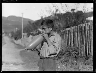 Image: Māori boy, possibly Moetu Otimi, blowing up a balloon, Waikato