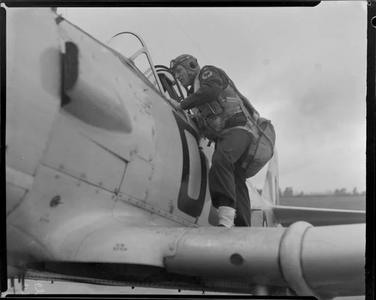 Image: Cadet pilot A J King, alongside the cockpit of a Harvard aircraft, Wigram, Christchurch