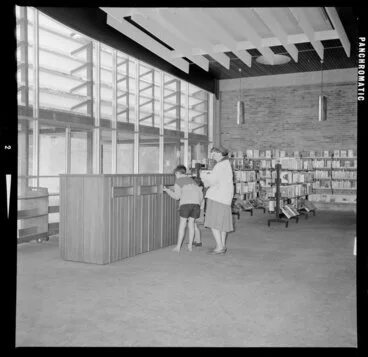 Image: Boy and woman returning books in the Gisborne Public Library