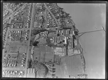 Image: Close-up view over the New Zealand Refrigerating Company, Imlay Freezing Works Imlay Place, Wanganui, with stock pens and yards, and effluent treatment ponds, and stacks of timber next to residential housing with Heads Road, Balgownie Avenue and Wordsworth Street, located beside the Wanganui River with wharf for loading ships