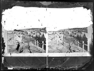 Image: Stereoscopic photograph of a unidentified residential area, featuring a street with terraces on both sides and wooden cottages