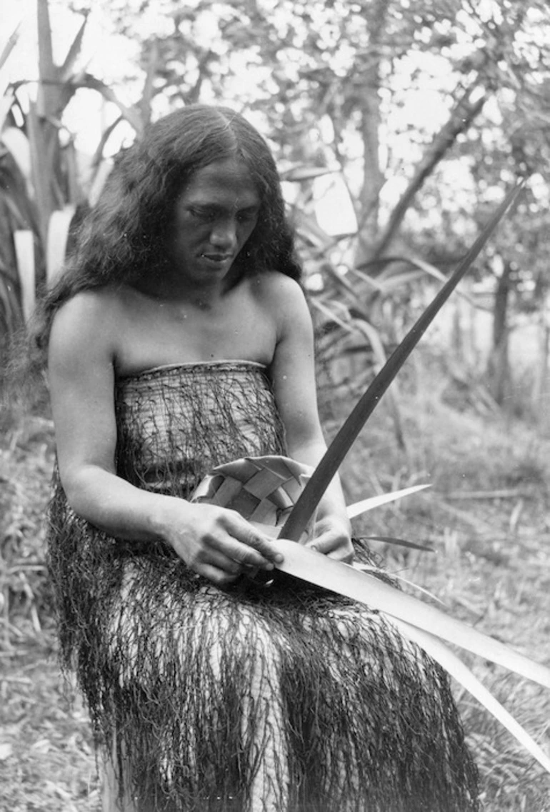 Image: (Rakara?) Chadwick, wearing a korowai, weaving a small flax basket