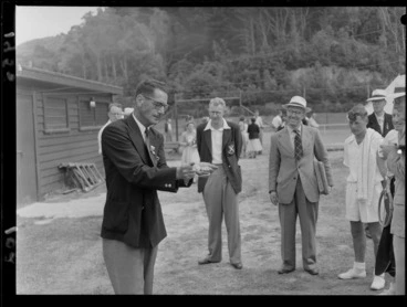 Image: Mr V Salek demonstrating the use of a dowsing rod to a group, at a national tennis tournament, location unidentified