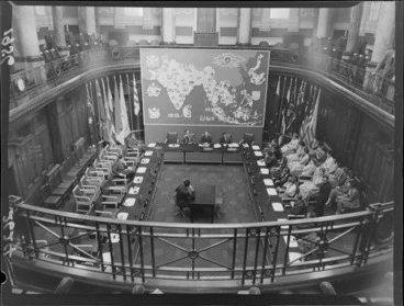 Image: Testing headphones before Colombo Plan conference, Wellington, including map of the world decorated with national crests