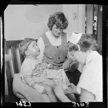 Image: Nurse attending to a small boy, with mother comforting child, all unidentified, at an unidentified hospital