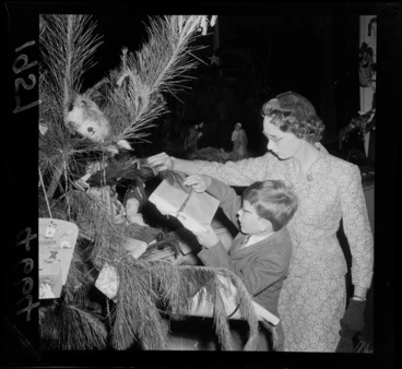 Image: Little boy with his Mum attaching a Christmas present to the Christmas tree