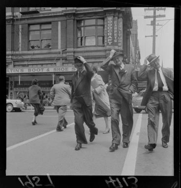 Image: Men holding their hats in a Wellington wind