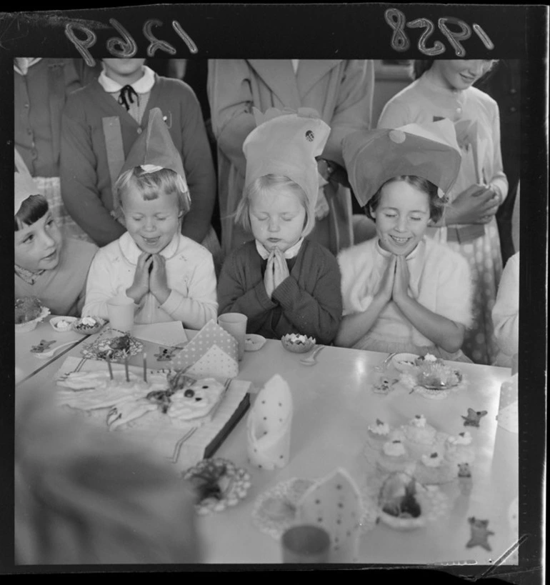 Image: Kindergarten children saying grace before eating during a party at Karori West School, Wellington