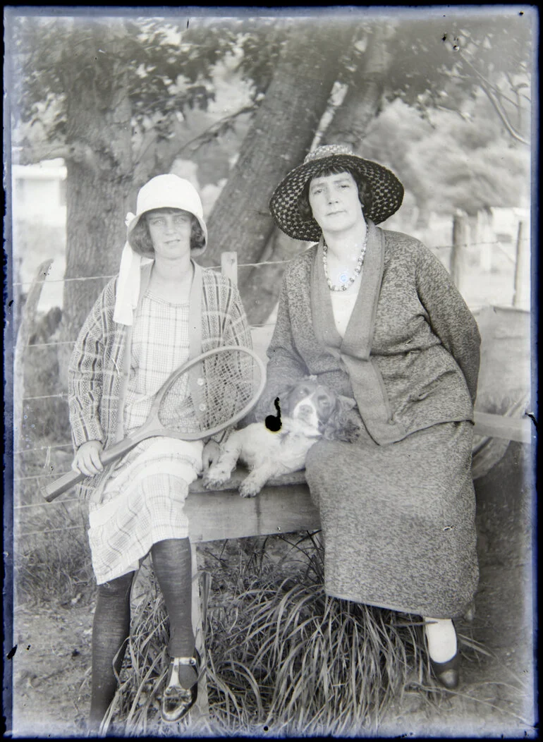 Image: Two women seated on bench with tennis racquet
