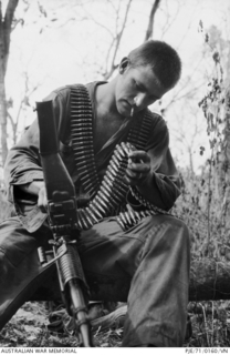 Image: South Vietnam. March 1971. Private (Pte) Grant Burrows of Korumburra, Vic, cleaning his M60 machine gun. The day before this photograph was taken, the gun was used to save the life of Pte Burrows ..