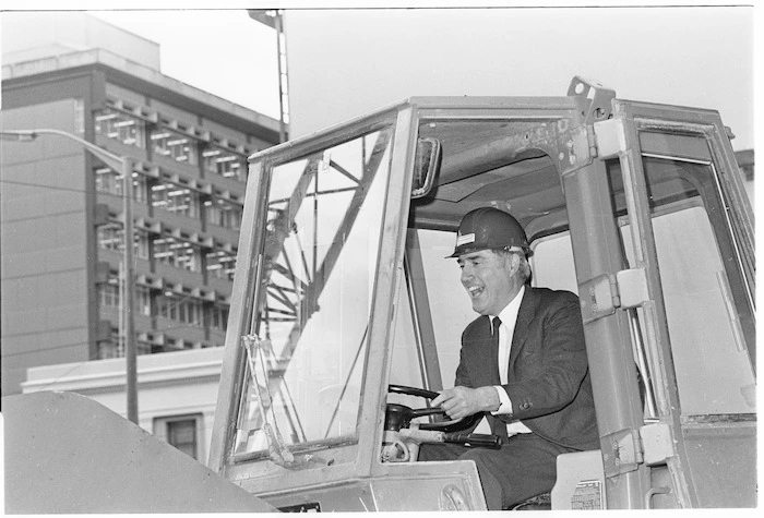 Justice Minister Geoffrey Palmer driving a front end loader on the construction site of the new Wellington District Court - Photograph taken by Merv Griffiths
