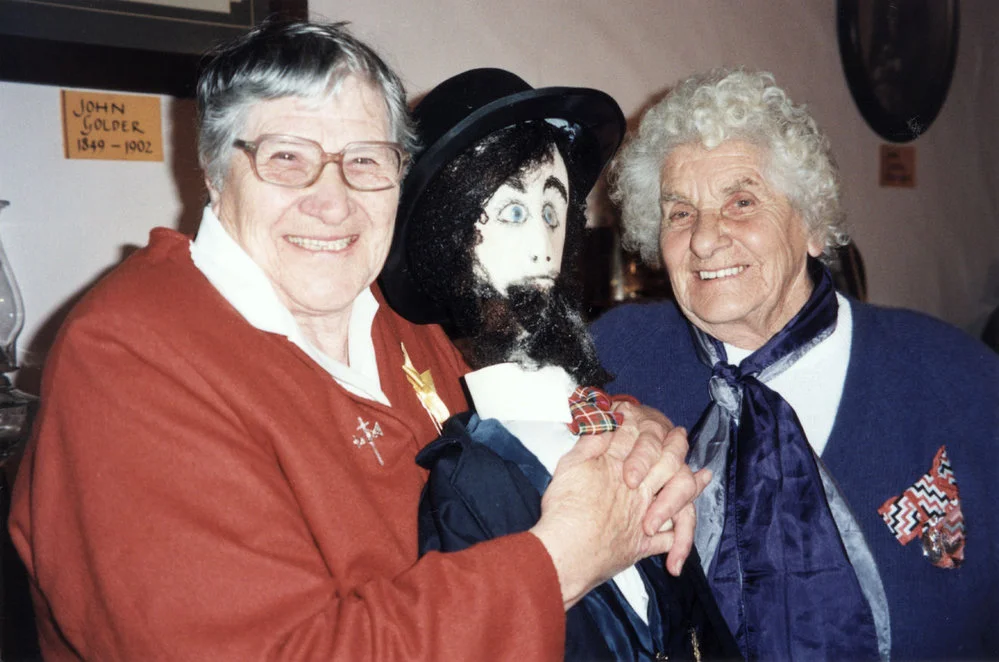 John Golder's grand-daughters present figure of John to the cottage museum.