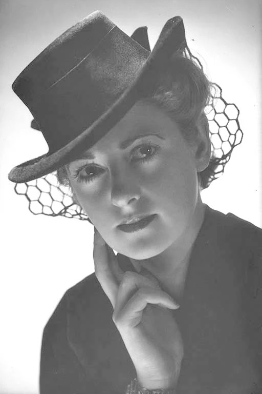 Head and shoulders portrait of a model wearing a hat and outfit for George Courts Limited